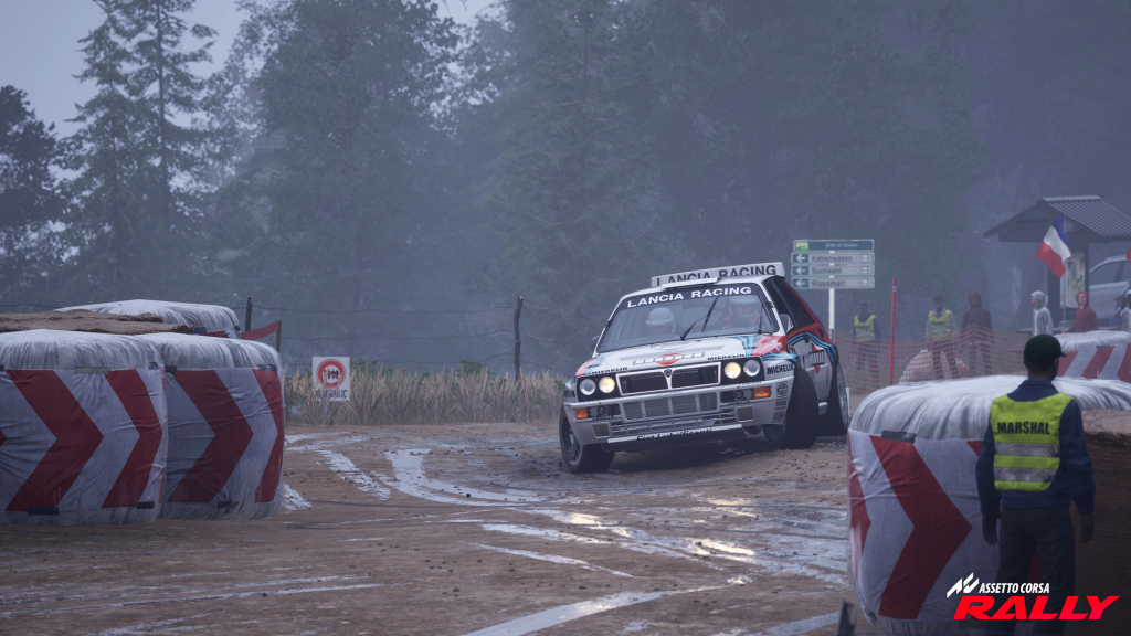 A Lancia Delta Integrale rally car powers through a tight, muddy corner during a stage in Assetto Corsa Rally. The car slides aggressively on the wet gravel surface, kicking up dirt as spectators and marshals watch from the sidelines. Tall pine trees and misty weather create a dramatic rally atmosphere, showcasing the game’s realistic lighting, detailed environments, and intense rally action.